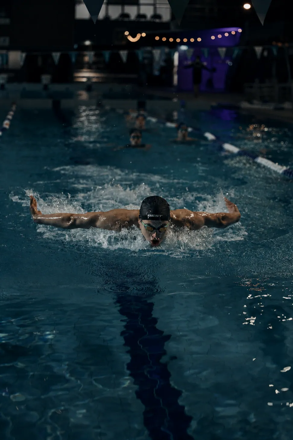 Swimmer powering through a butterfly sprint wearing a BEST Performance Dome Cap