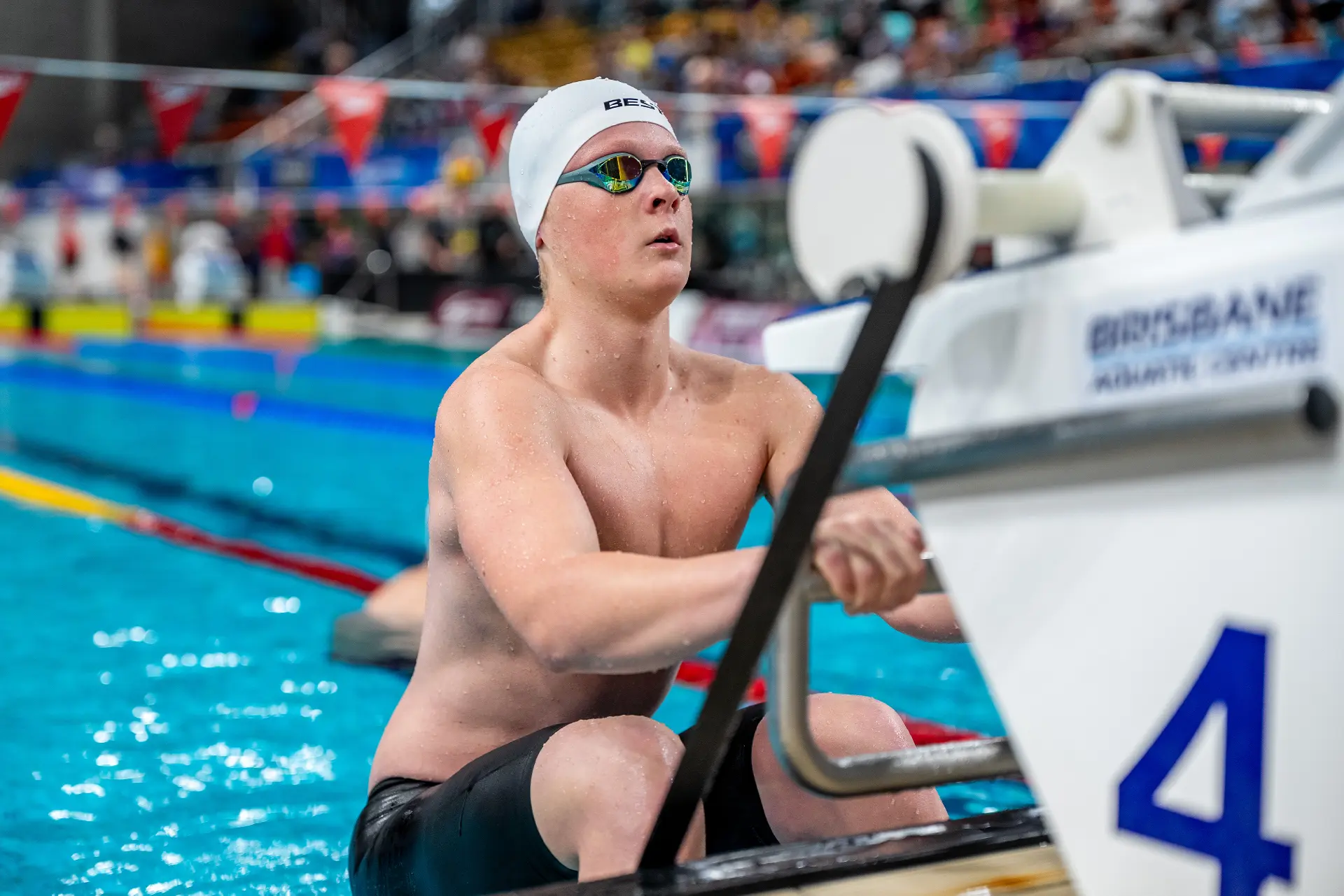 Swimmer in a white BEST Performance Dome Cap behind the blocks