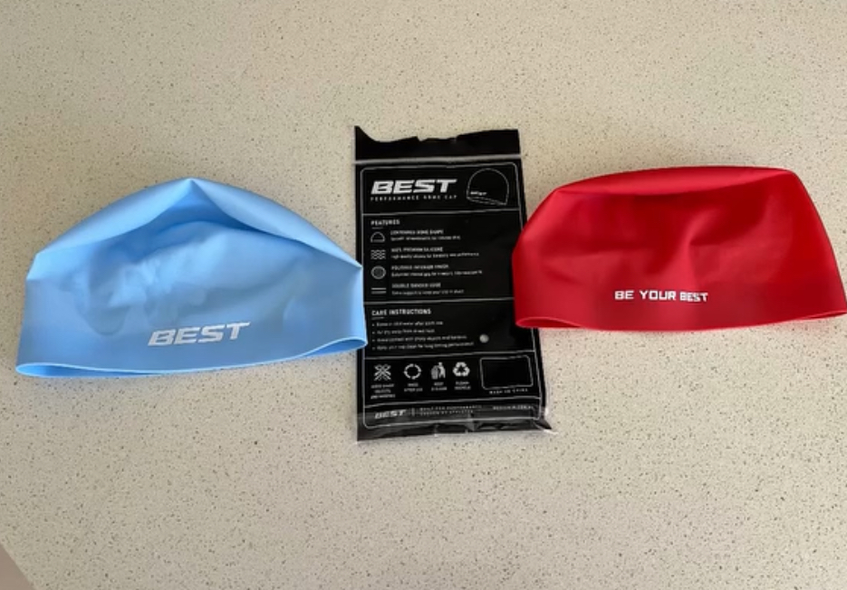 Black, navy and white BEST caps resting on the pool edge
